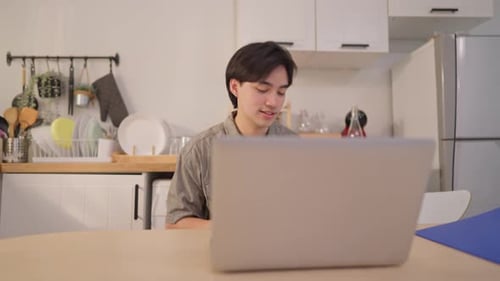 Man Video Conferencing on Laptop in Bright Kitchen