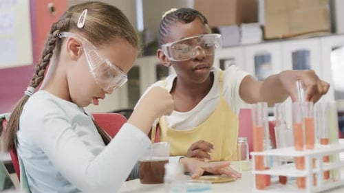 Happy diverse schoolgirls doing experiments in lab in slow motion at elementary school