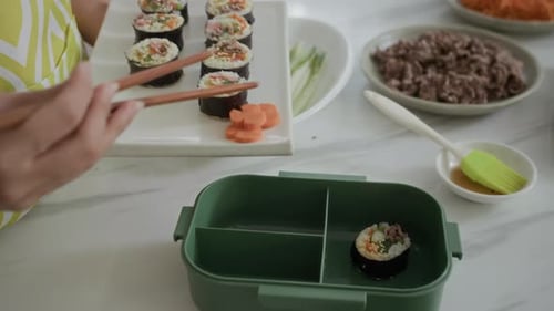 Hands of Girl Putting Self-made Kimbap in Lunchbox at Kitchen
