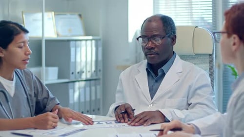 Mature Black Doctor Leading Meeting with Colleagues in Medical Office