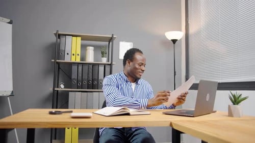 Man Reviews Documents and Types at Office Desk