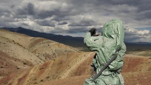 Person in Hazmat Suit Observes Barren Landscape