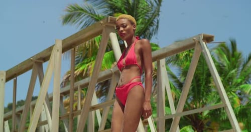 In the midst of tropical beauty, a girl with dark skin dons a red bikini on a Caribbean white sand b