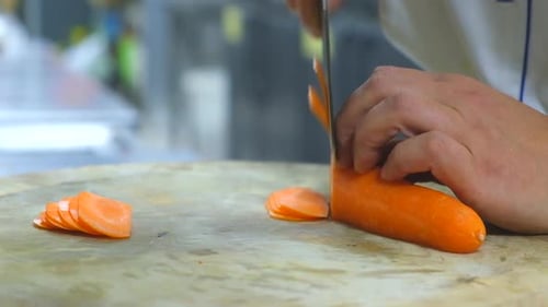 Hands Slicing an Orange Carrot on a Cutting Board