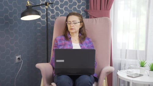 Woman Works on Laptop in Comfortable Armchair