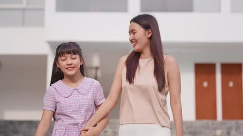 Asiatische liebende Mutter, die mit ihrer kleinen Tochter draußen im Garten spazieren geht.