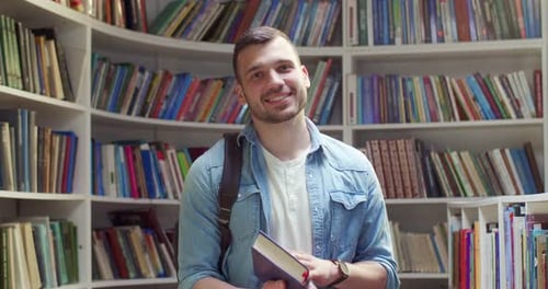 Portrait Shot of Happy Caucasian Young Handsome Male Student with Backpack Holding Textbook and