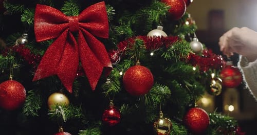 Decorating Christmas Tree with Red Ornaments and Bow