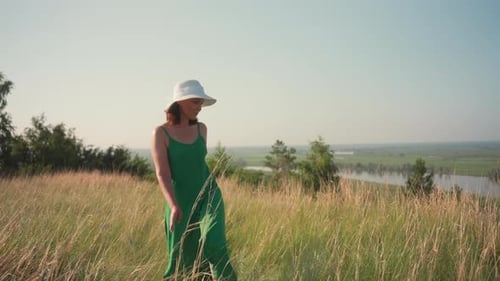 Woman Walking Grassy Hill Touching Grass Overlooking River Landscape