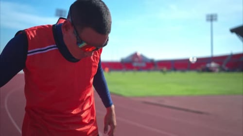 Disabled athletic man stretching and warming up before running on stadium track