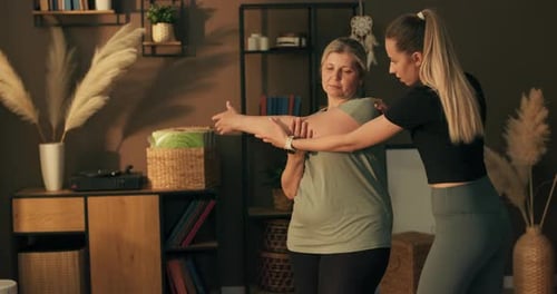 Fitness Coach Helping Senior Woman Stretching at Home