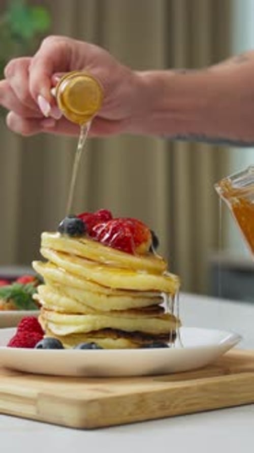 Honey Being Poured Over a Stack of Pancakes