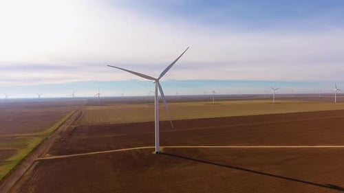 Cinematic drone shot of a field of wind turbines or wind farm