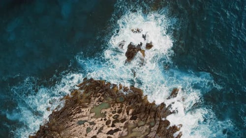 Crashing sea waves splash over jagged shoreline at rocky coast