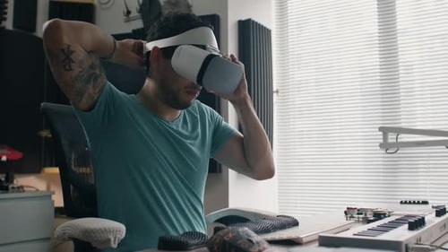 Putting on VR headset to make music in a virtual world at home studio