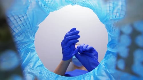 Medical Professional Discards Gloves in Trash Receptacle
