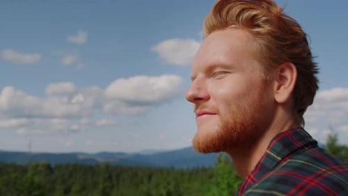Porträt eines entspannten Mannes, der die Berglandschaft im Sommer genießt. Fröhlicher männlicher Reisender, der grau aussieht...