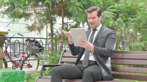 Businessman Using Tablet for Video Call in Park