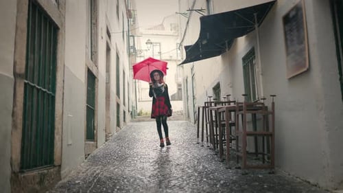 Stylish Woman with Red Umbrella Walking on Rainy Street