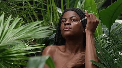 Woman Applies Serum in Tropical Greenery