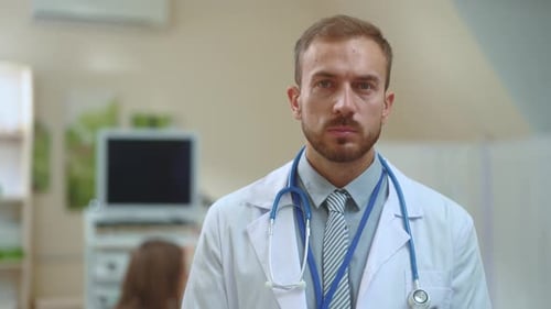 Portrait of Handsome Young Professional Doctor Looking Serious Into Camera Inside His Office