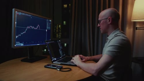 Man in Trader Home Office Monitor and Laptop are on Table Trading Program or Exchange Male Analyzes