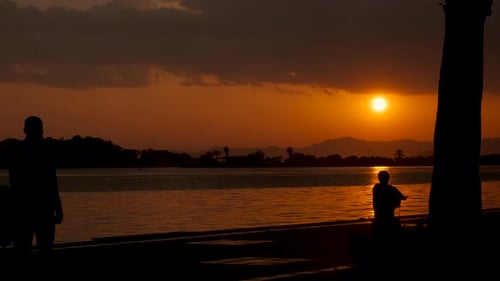Silhouetten ruhender Menschen in exotischer Bucht.