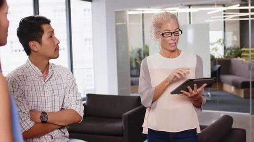 Discussing project details, colleagues collaborating in modern office with tablet