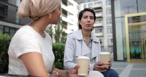 Female Arabic friends having coffee together outdoors
