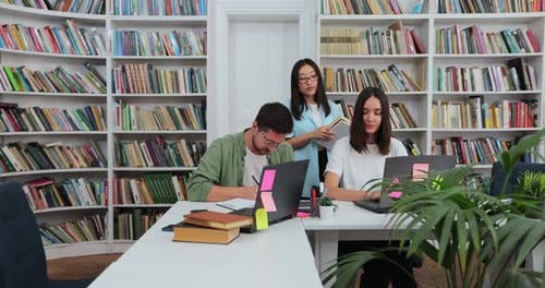 Three Students Working Together at Library Table
