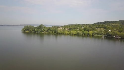 Aerial View of a Small Village in Rural Area Between Green Trees on the Shore of a Big Lake