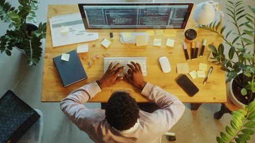 Von oben nach unten, wie Programmierer am Computer am Schreibtisch im Büro codiert