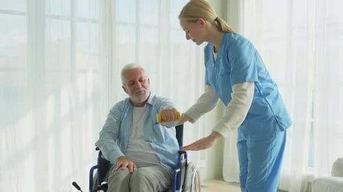 Senior Man Exercising Arm with Assistant in Home