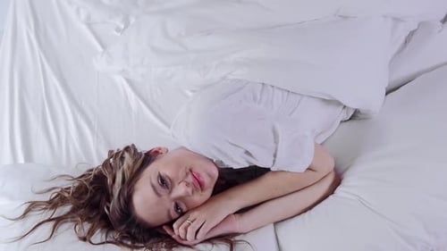 Cute Young Woman Sleeping in Bed Waking Up and Smiling at Camera