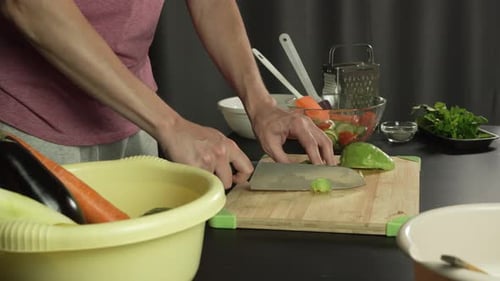 Hands of middle man european slices a avocado with kitchen knife on cutting board, left side view