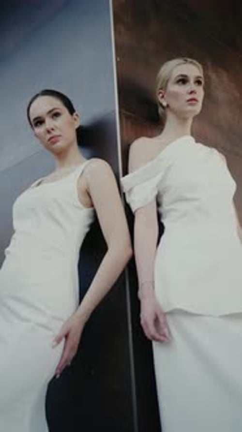 Two Women in White Dresses Posing in Urban Setting