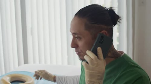 Un herpetólogo tatuado habla por teléfono inteligente mientras toca una pitón albina