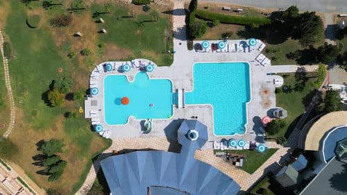 Topdown Aerial View of an Outdoor Swimming Pool Complex with Lounge Chairs Umbrellas and a Small