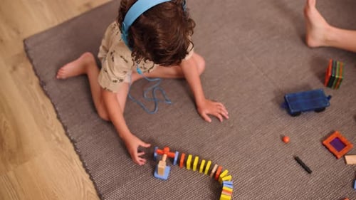 Young Boy Playing with Dominoes and Building Blocks