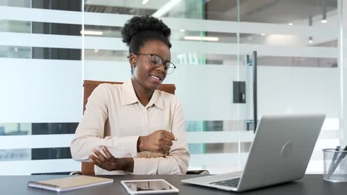 African american businesswoman suffering from elbow pain sitting at desk in office