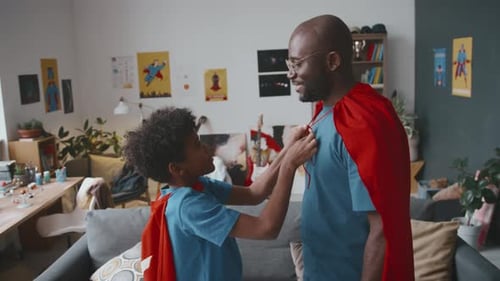 Boy Helps Man With Superhero Cape Indoors