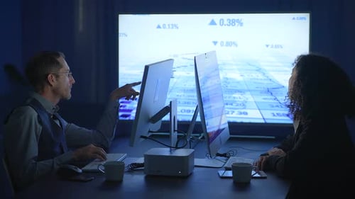 Adults Looking at Statistics on Computers at Night