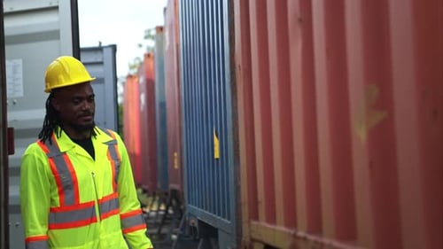 Construction Worker Talking and Gesturing Next to Shipping Containers