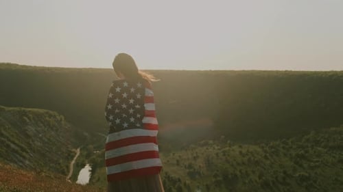 Young Woman with American Flag Overlooking a Valley at Sunset