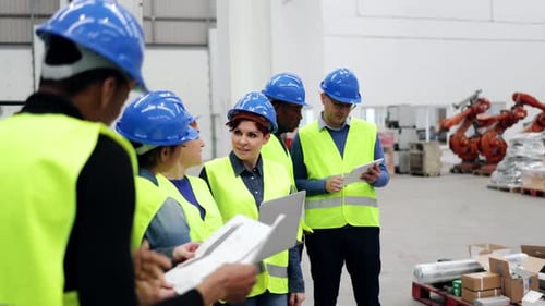 Gemischtrassige Ingenieure arbeiten in einer Einrichtung für Roboterautomatisierung - Industrierobotertechnologie
