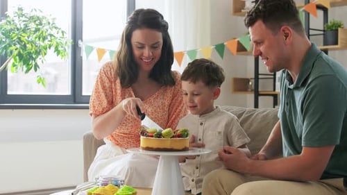 Family celebrating birthday cutting cake at home