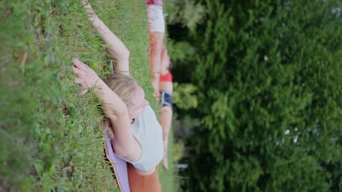 A Blonde Woman with Friends Doing Yoga on the Grass Vertical View