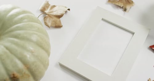 Empty frame with copy space, pumpkin and autumn leaves against white background