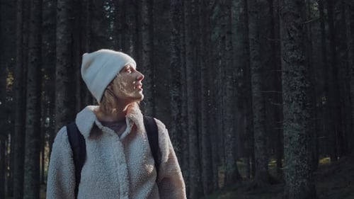Nahaufnahme einer jungen Frau mit blonden Haaren und Rucksack beim Wandern im unberührten grünen Wald