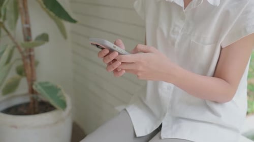 Woman Using Smartphone Inside Near Plant
